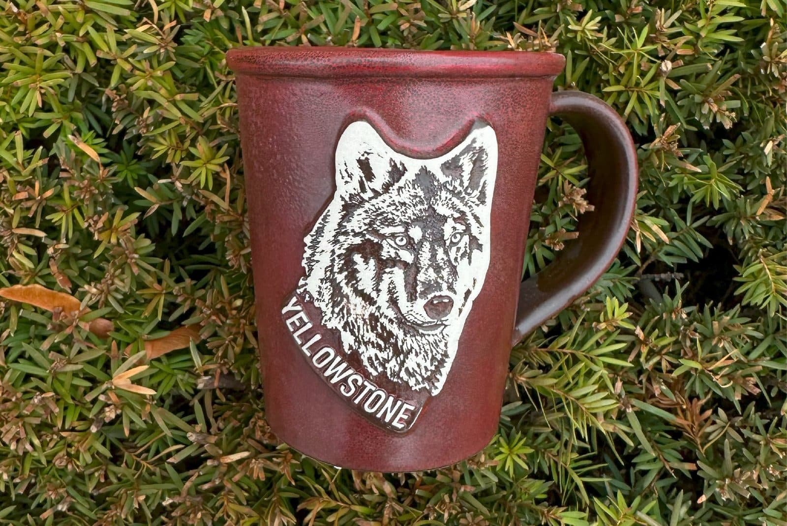 Yellowstone wolf medallion on a wine-red ceramic mug