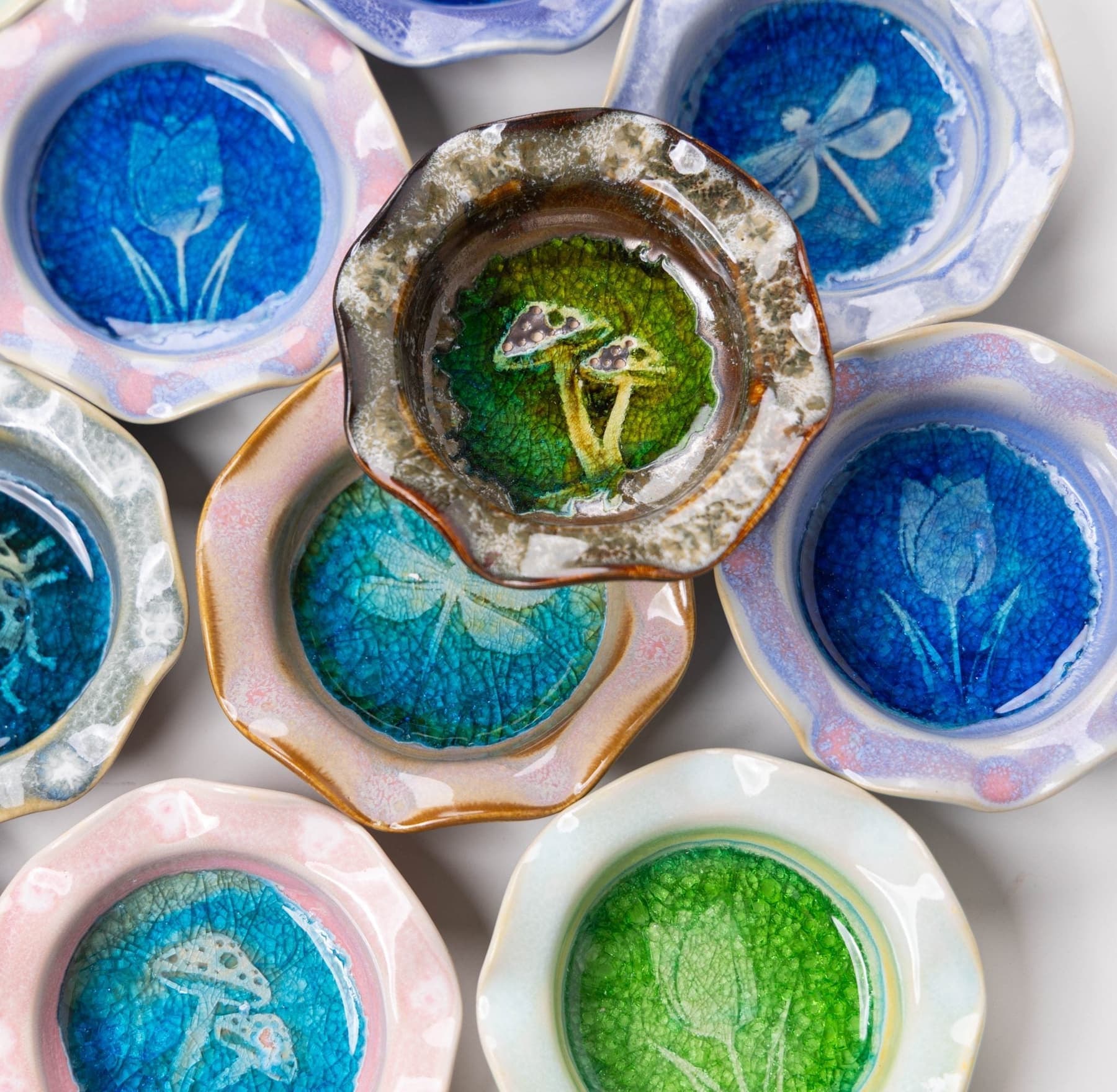 An overhead spread of JJ Potts trinket dishes stamped with tulip, dragonfly, and mushroom designs