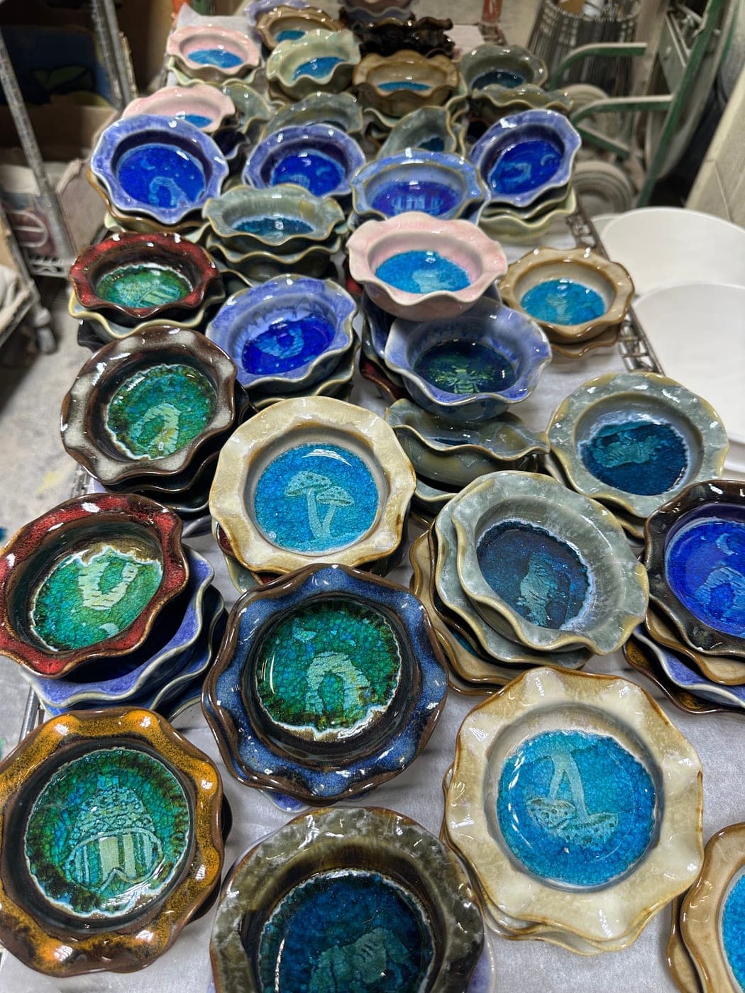 Racks of finished trinket dishes stacked by glaze color in the JJ Potts studio